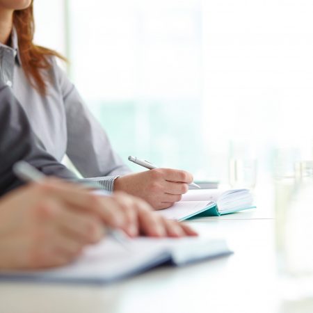 Hand of businesswoman with ballpoint over open notebook at convention
